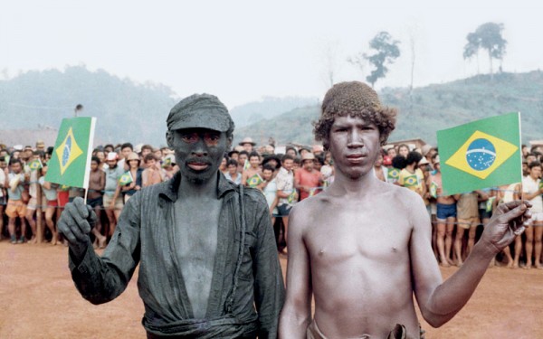 Dois garimpeiros, um deles coberto da lama de ouro preto, se preparam para receber a visita de João Figueiredo