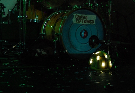Bateria da banda ao lado do capacete de luzes usado por Tatá nos shows