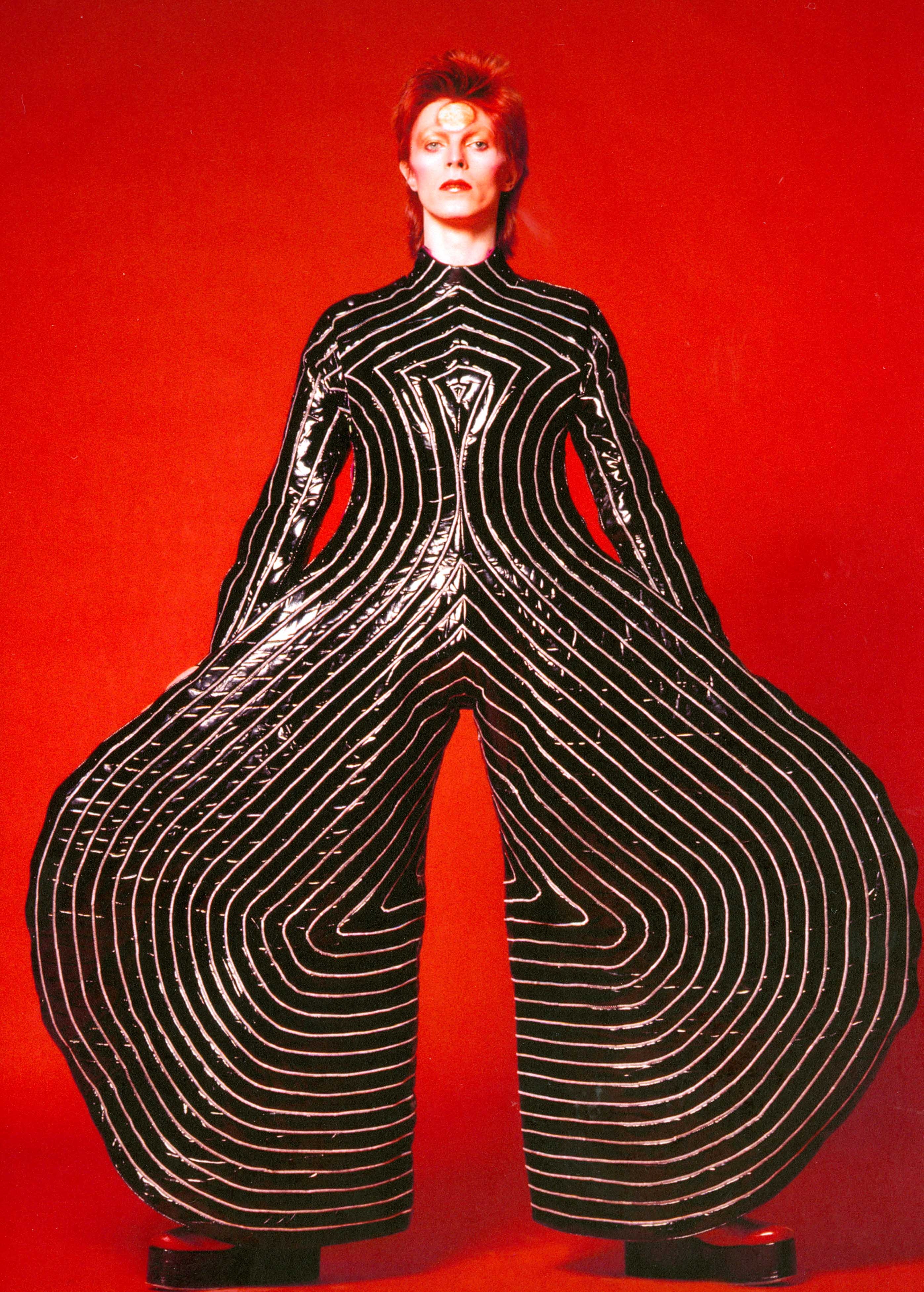 TRAJE DE VINIL “TOKYO POP” USADO NA TURNÊ ALADDIN SANE (1973) Graças a seu porte elegante e à seriedade de sua expressão, Bowie sabe dar densidade & seriedade para looks absurdos como esse assinado por Kansai Yamamoto. Triunfal, maravilhoso!!