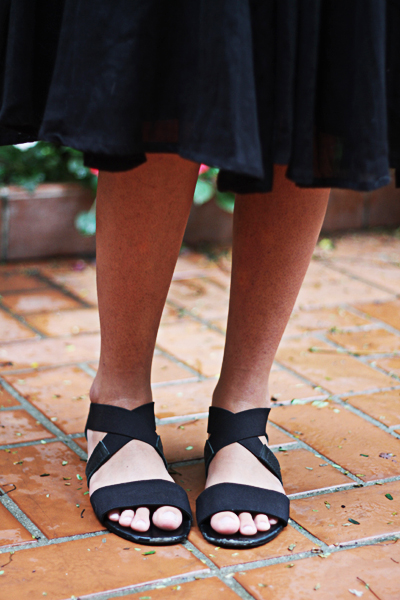 Nos pés, para combinar com uma saia de comprimento quase longo, uma sandália de tirinhas preta baixa