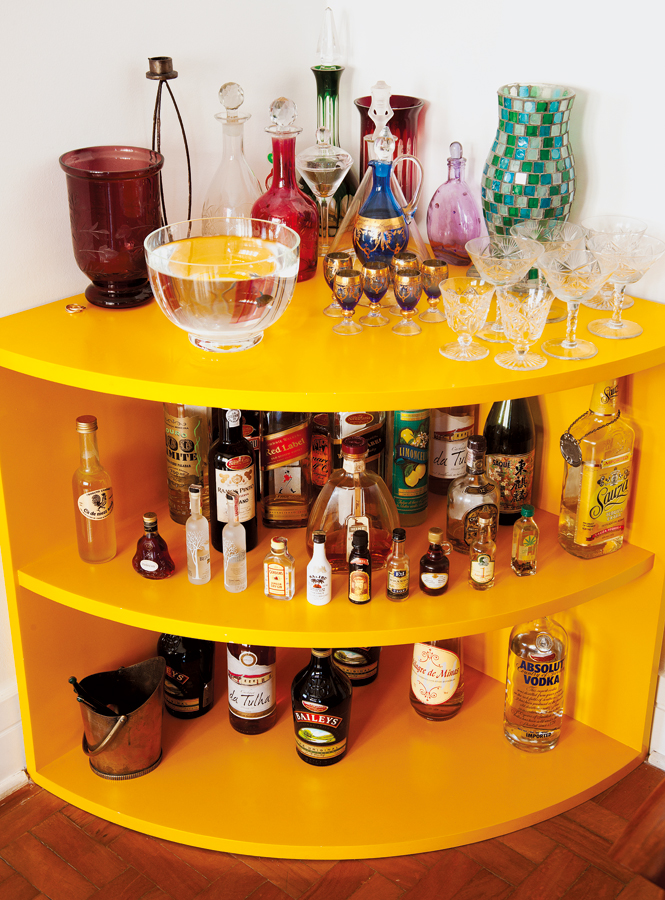 Vai uma bebidinha? l O bar de laca amarela, também feito pelo marceneiro Adelmo, armazena as bebidas, a coleção de garrafas e vasos e o peixinho de Manuela