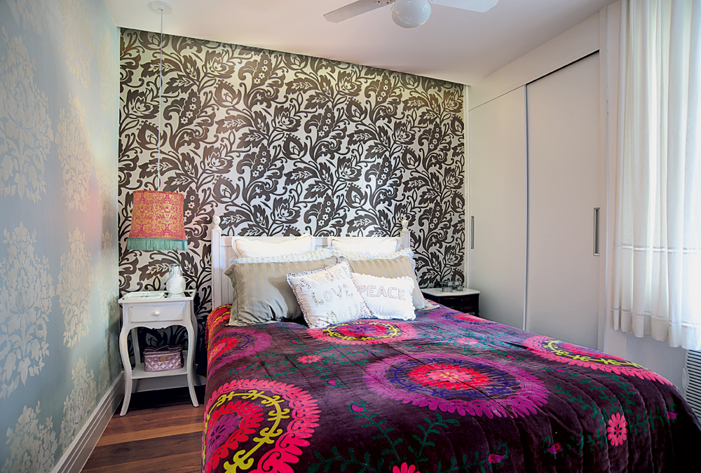 Estampado:  O quarto do casal tem dois papéis de parede diferentes, ambos da Orlean e com textura aveludada, que fazem uma composição com o lustre da Rupee Rupee. A colcha é da AREA Objetos
