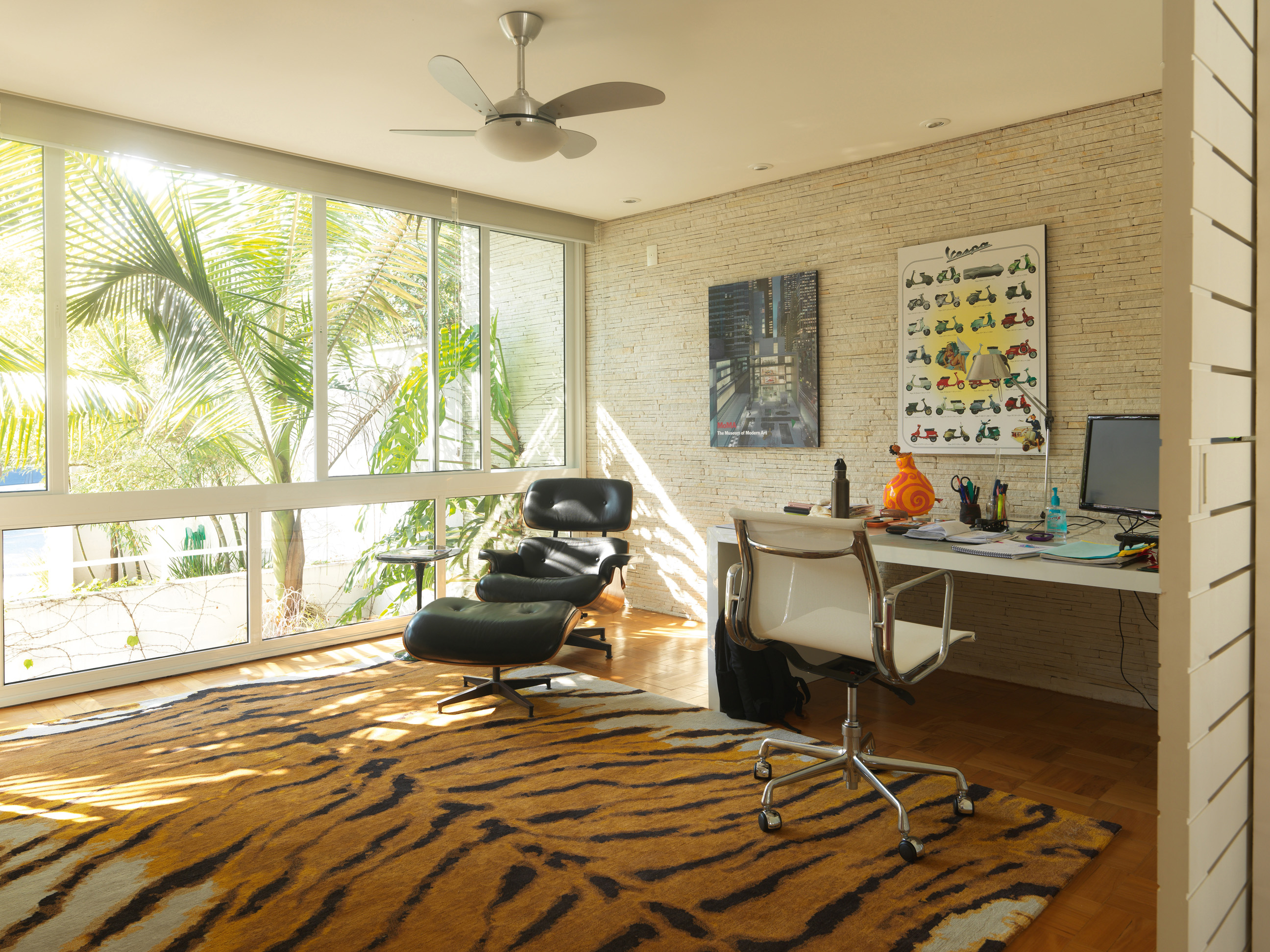 Tropical - Escritório de Lina, onde era o showroom de sua empresa até pouco tempo atrás. O tapete com estampa de tigre, de lã tibetana, é da coleção de Lina. A poltrona e a cadeira são de Charles Eames e a mesa foi feita por marceneiro
