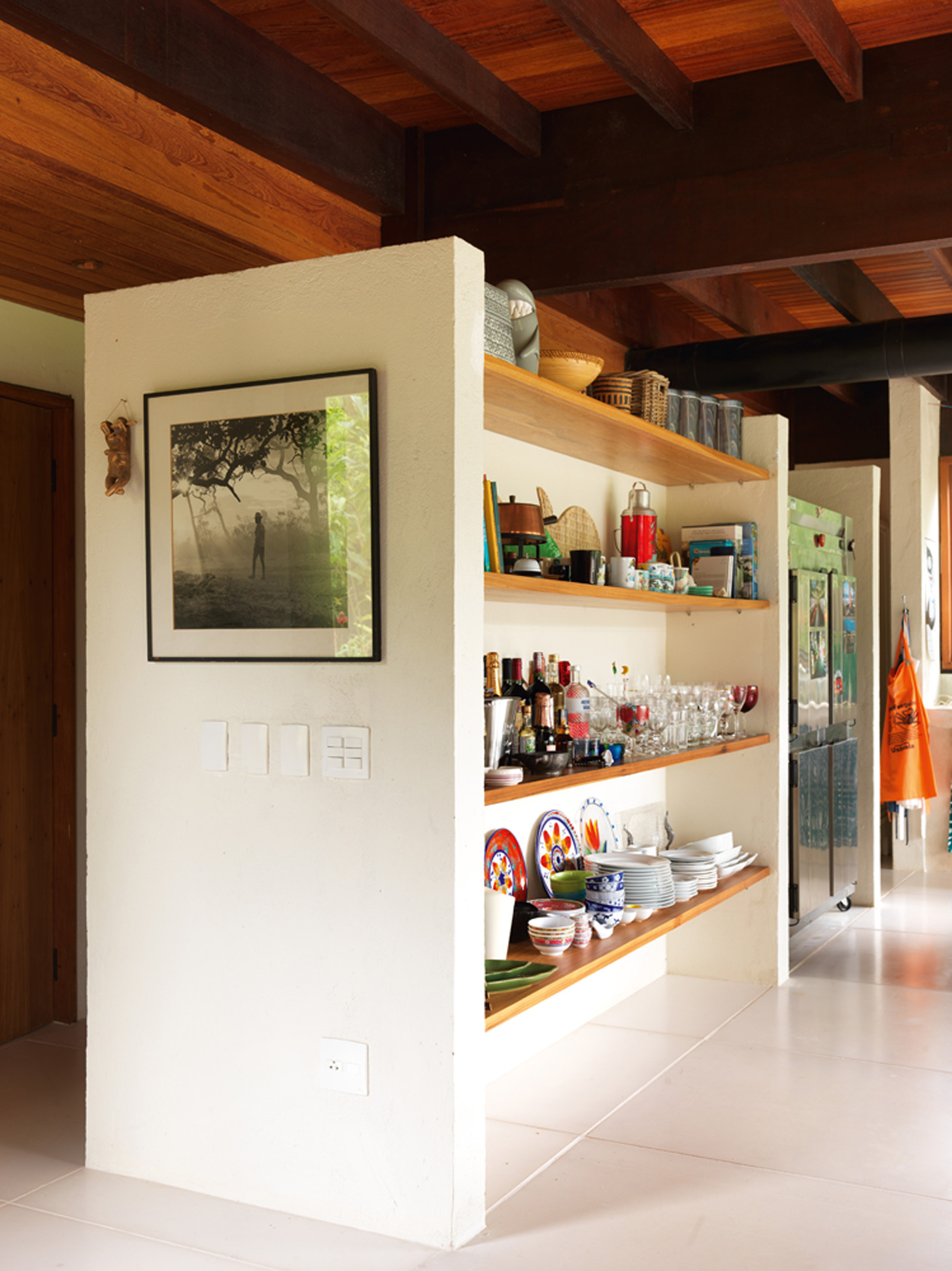 À mão: Na cozinha, as estantes de madeira fazem as vezes de armários e deixam os objetos à mostra, fáceis de pegar. Fotografia de Marcos Prado, amigo da família