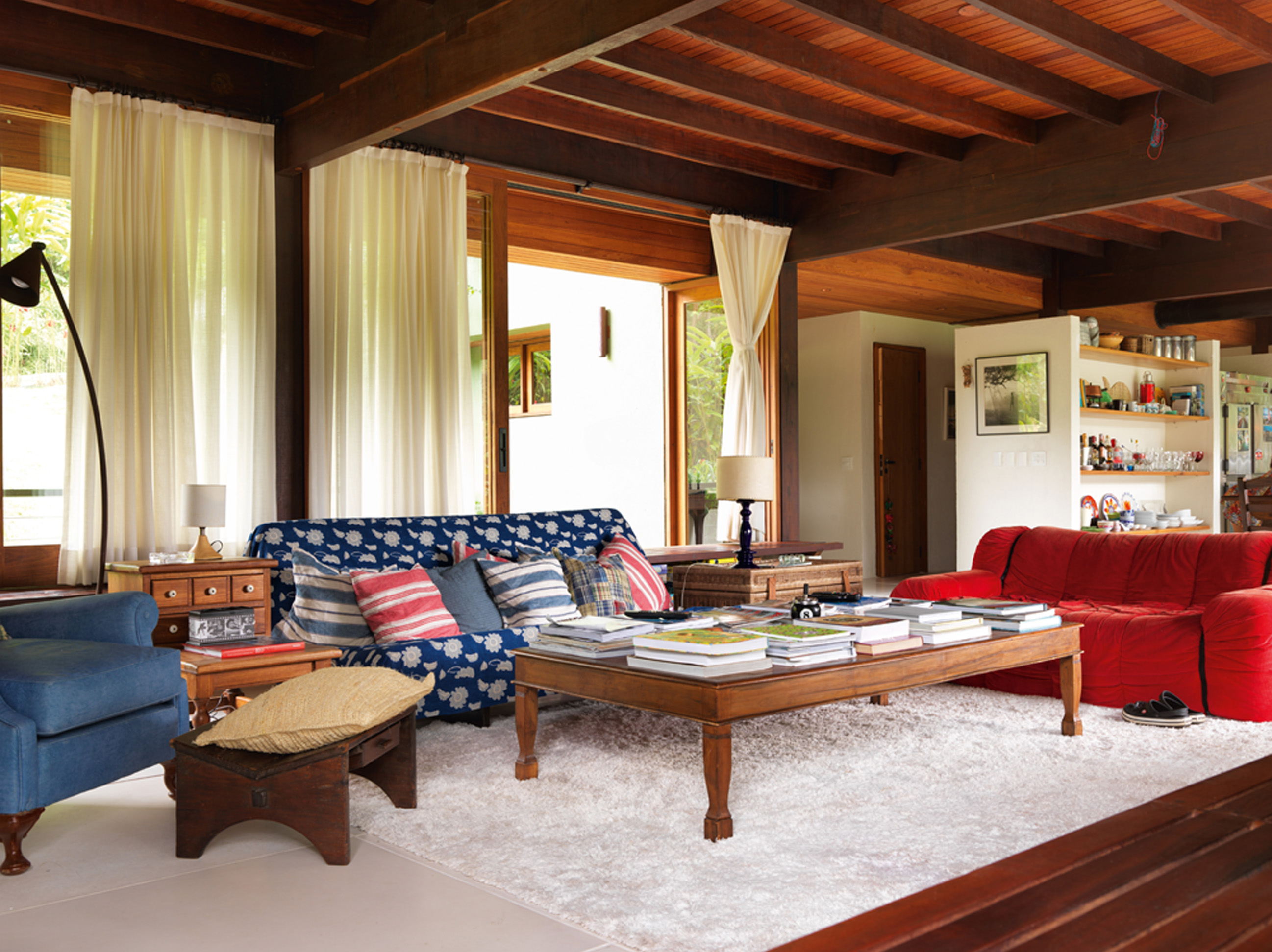 Senta lá: Outra perspectiva da ampla sala. O sofá vermelho é da Forma e o sofá coberto com o tecido é da Futon Company