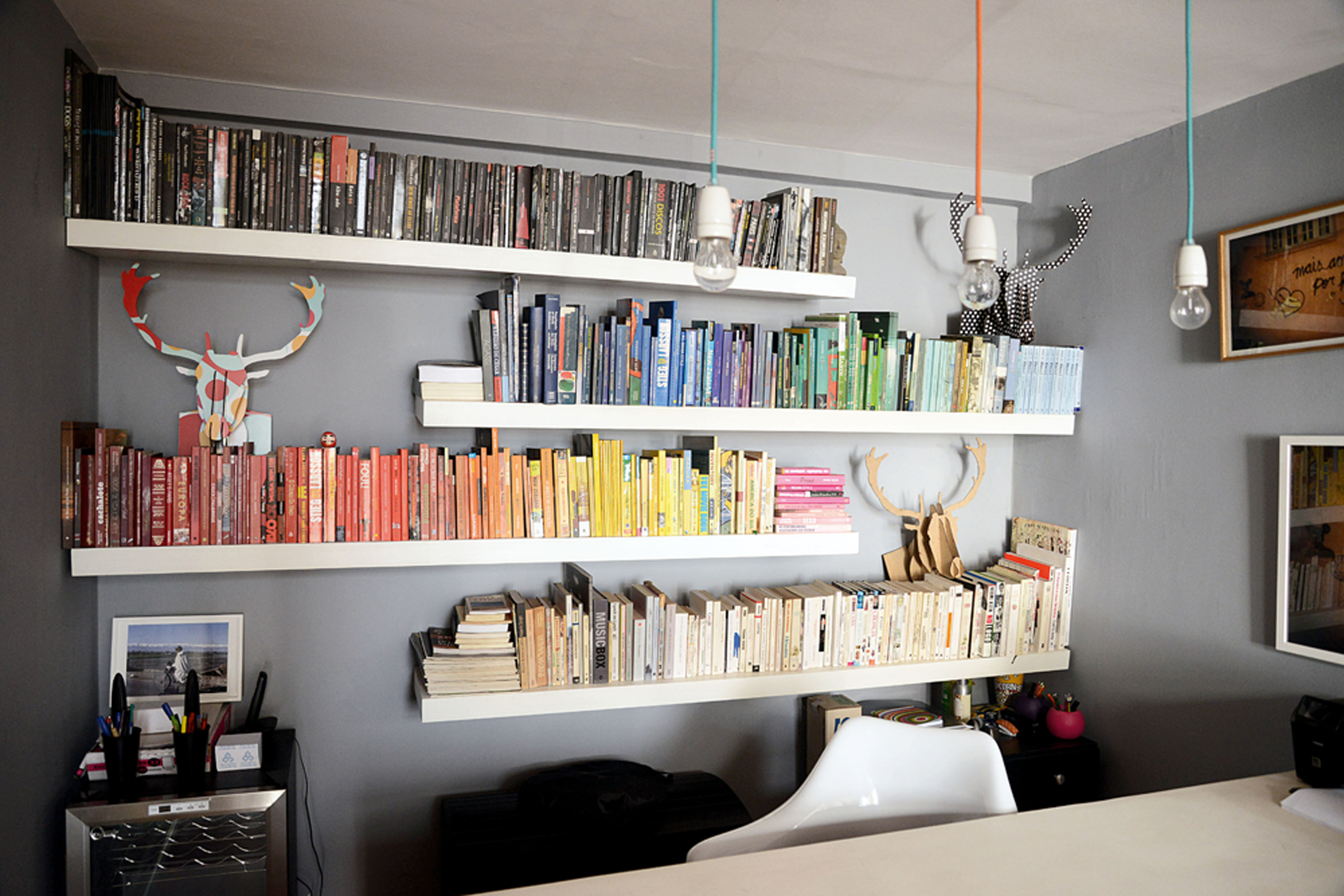 Rainbow: Mariana organizou os livros do escritório por cores, para que se destacassem ainda mais sobre a parede cinza