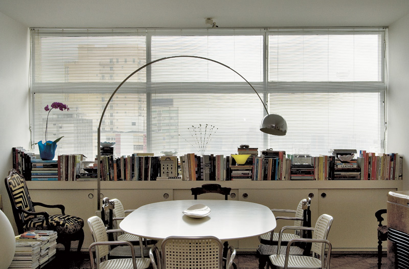 Na sala de jantar, mesa e cadeiras Vico Magistretti e luminária Arco, de Achille Castiglioni. O aparador sob o janelão guarda seus muitos livros de arte e moda