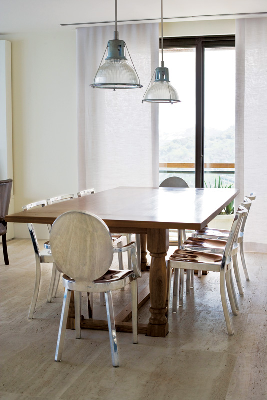 Na sala de jantar, a mesa de madeira é da Elle et Lui Maison. As cadeiras de aço, do designer Philippe Starck, foram compradas na Forma