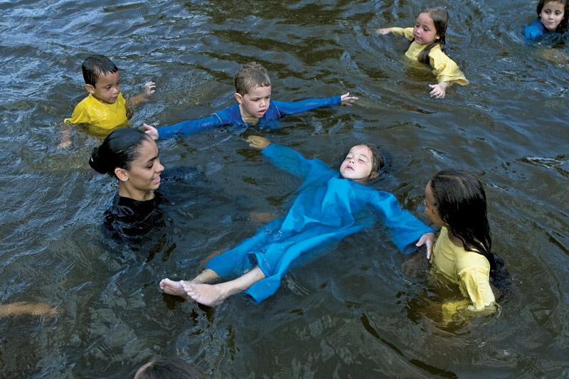 Bruna, 19, com as crianças na piscina do sítio do fundador da igreja. Os seguidores do pastor Marcos só se banham de camisas de mangas compridas e calças (homens) e roupões (mulheres)