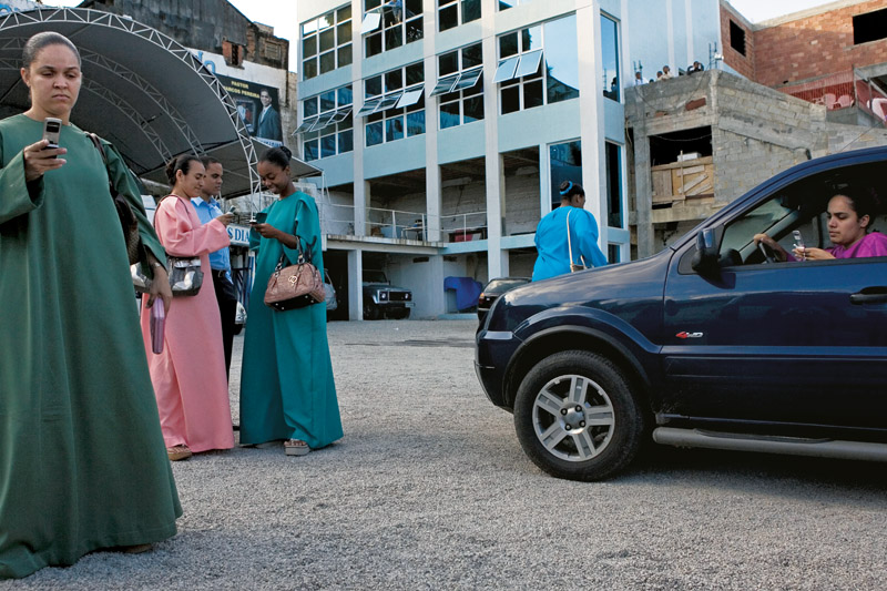 Fabíola, 29, e outras irmãs, no estacionamento da Assembleia de Deus dos Últimos Dias (ao fundo): sandálias de salto e telefones celulares