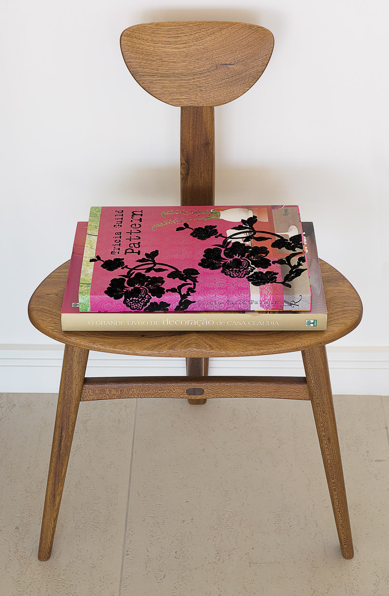 Livros de decoração sobre cadeira do designer Morito Ebine. São duas na sala, uma de cada lado da cômoda do Mercado livre