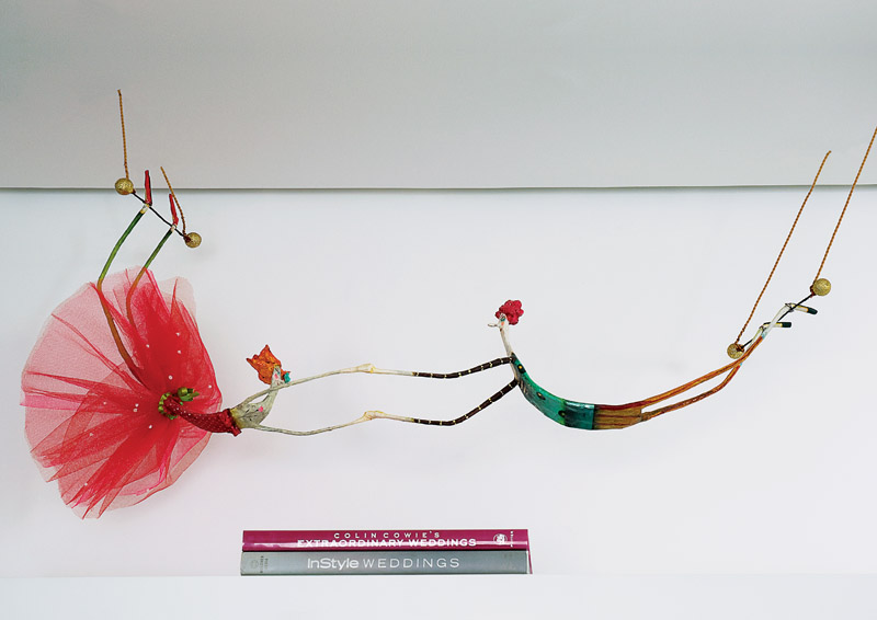 As trapezistas de papel machê são de Juliana Bollini, uma das artistas brasileiras preferidas de Lucila. Embaixo, livros sobre decoração de casamento