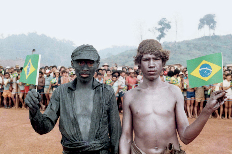 Dois garimpeiros, um coberto da lama de ouro preto, se preparam para a visita de João Figueiredo