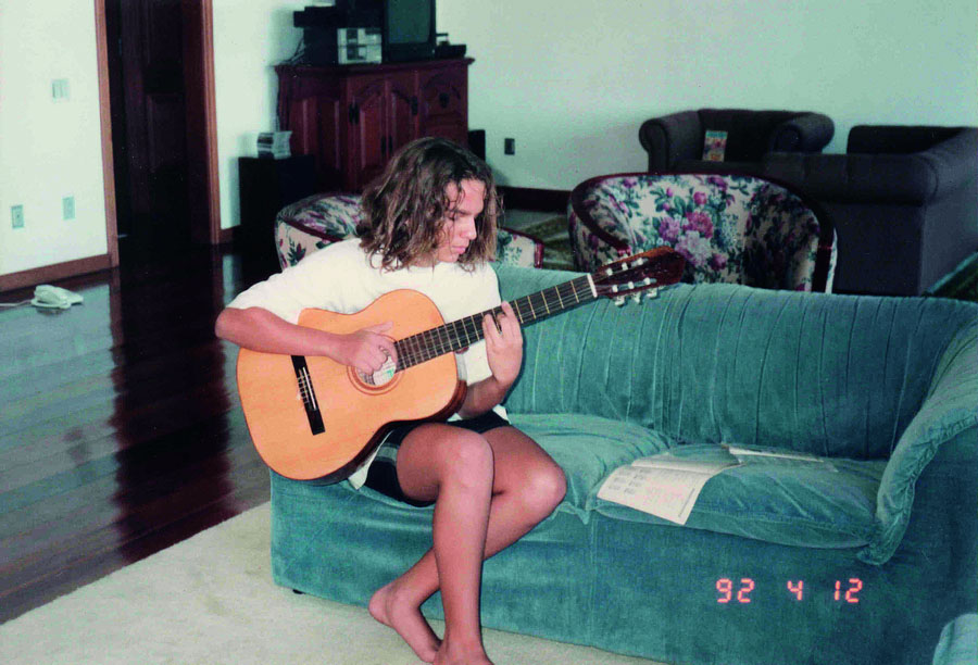 Estuda violão na sala de casa