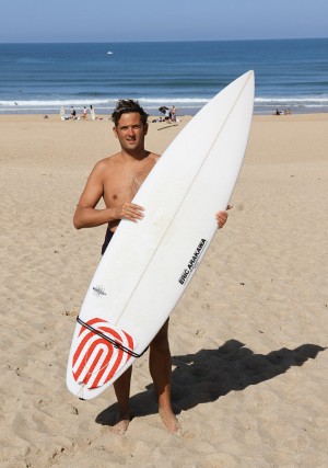 Thomas Green, o surfista australiano que fundou a comunidade gaysurfers.net, posando na areia