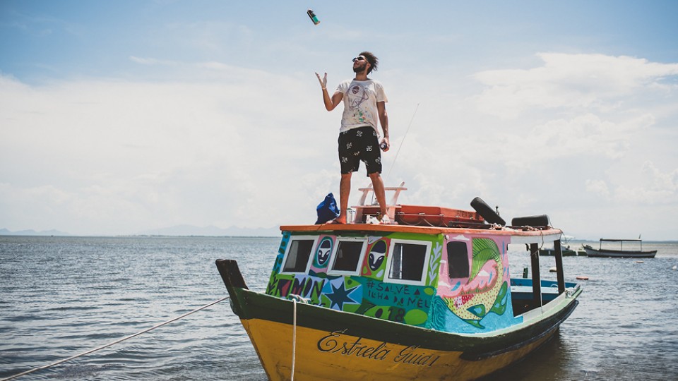 O grafiteiro Rimón Guimarães em um dos barcos pintados para a campanha Salve a Ilha do Mel