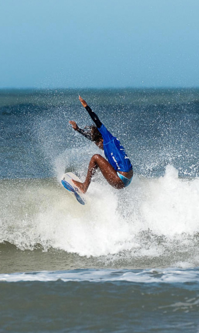 Surfista negra fazendo uma manobra no mar