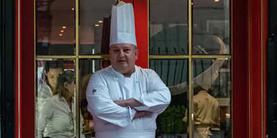 Erick Jacquin vestido de chef de cozinha em frente ao restaurante