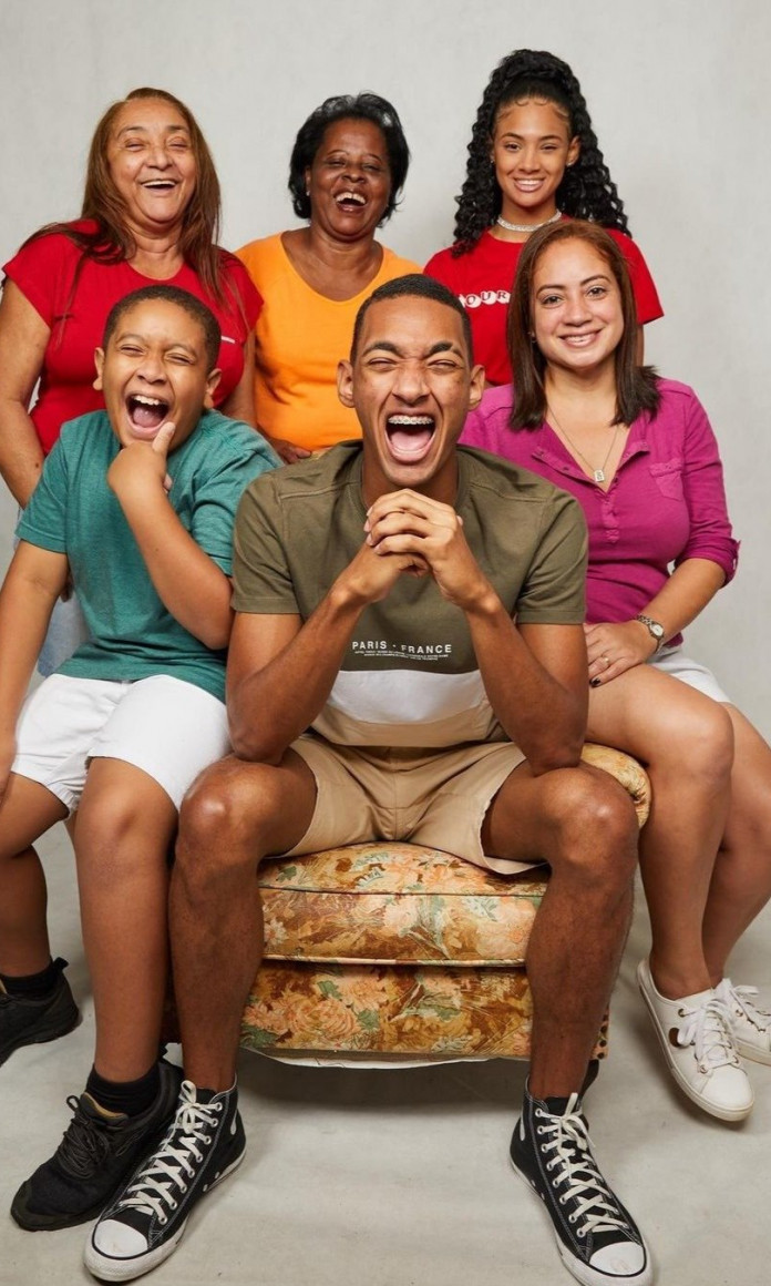 Família de seis pessoas com camisetas colorindo e sorrindo para a foto