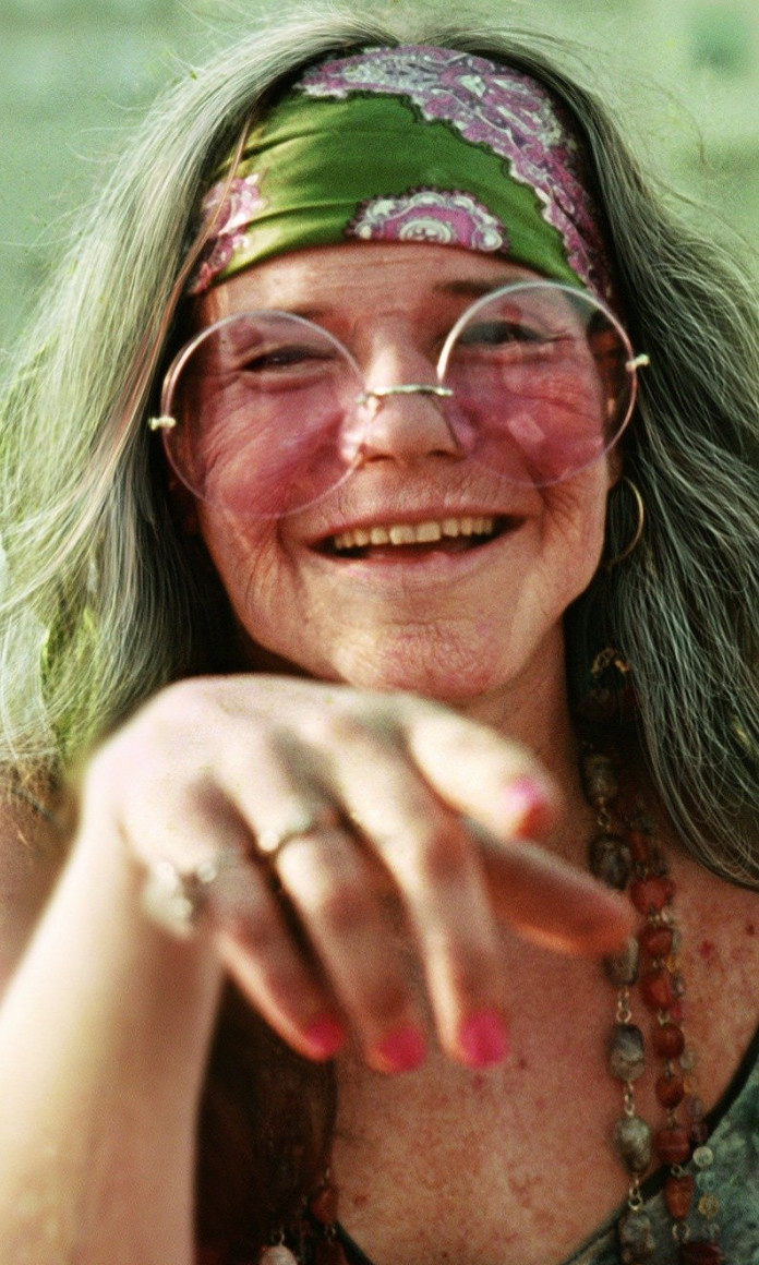 Janis Joplin como se tivesse envelhecido com cabelos brancos, rugas e óculos rosa