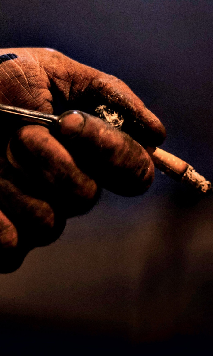 Mão suja segurando um cachimbo e um cigarro