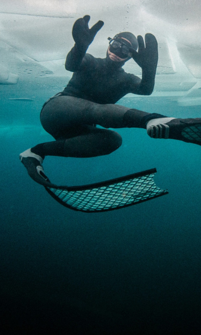 Mergulhadora debaixo do gelo com pes de pato e traje preto
