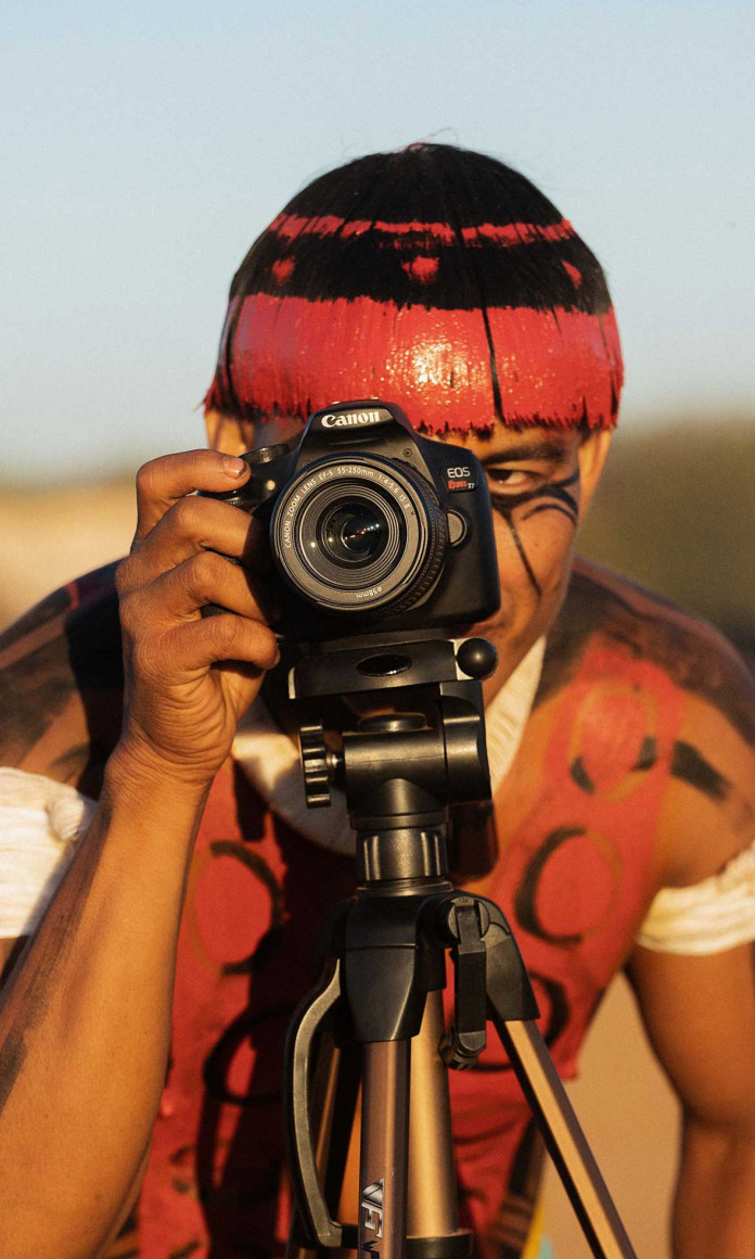 Homem indigena segurando uma camera de filmar