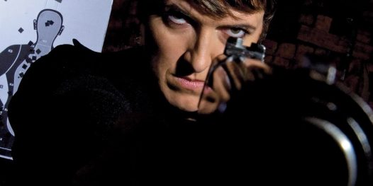 Ana no clube de tiro em que treina uma de suas atividades preferidas. Armas não faltam em sua vida: algemas, faca e canivete decoram a sala de sua casa