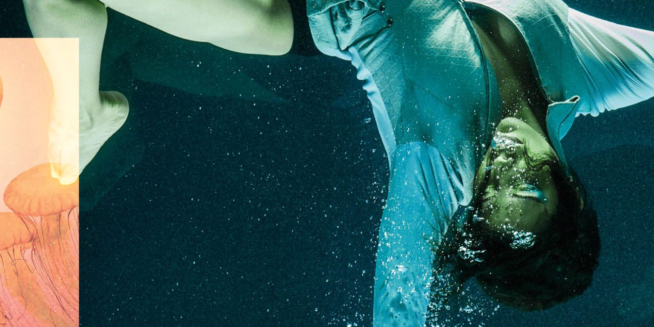 Mulher em frente a um aquário gigante cheio de águas vivas rosas