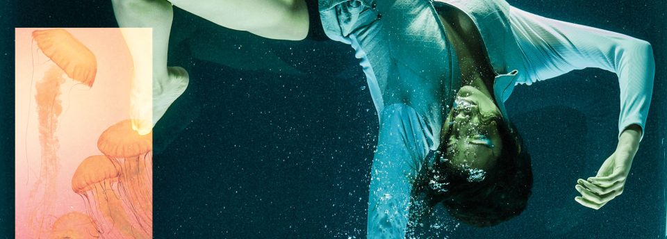 Mulher em frente a um aquário gigante cheio de águas vivas rosas